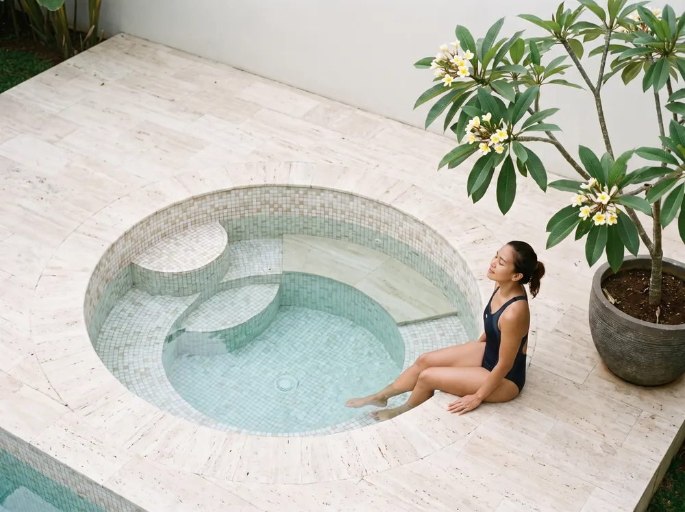 Cold plunge bulat mosaik dengan tangga bawah air di teras travertine rumah Tangerang